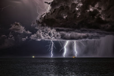 Scenic view of sea against storm clouds at night