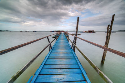 Pier over sea against cloudy sky