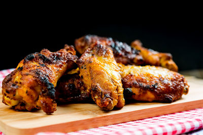 Close-up of chicken wings on cutting board against black background