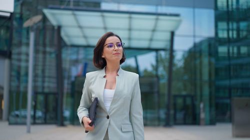 Successful young caucasian woman walking in central business district in modern city