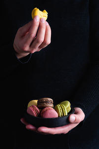 Close-up of hand holding ice cream cone against black background