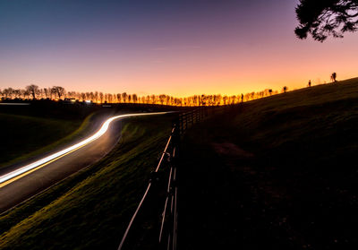 Railroad tracks on road against sky during sunset