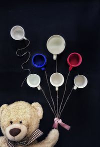 Close-up of teddy bear and cups against black background