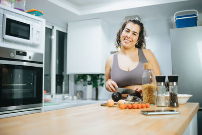 Portrait of smiling woman preparing food at home