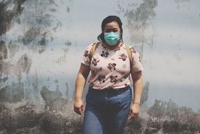 Portrait of young woman standing against wall