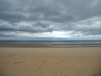 Scenic view of beach against cloudy sky