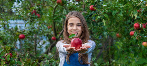 Portrait of young woman picking apple
