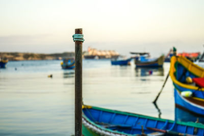 Close-up of wooden post by sea against sky