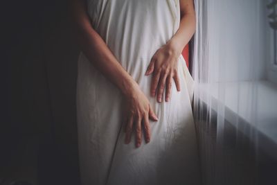Midsection of woman with white clothing standing at home