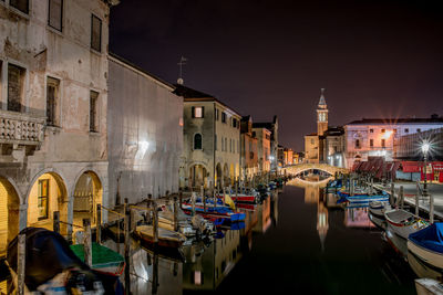 Boats moored in canal by buildings in city, like venice