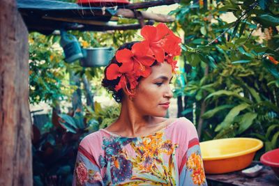 Woman wearing red flowers in hair against plants