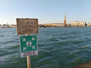 Information sign by sea against clear sky