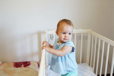 Cute girl sitting on bed at home