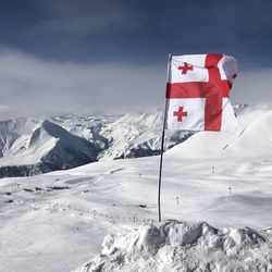Flag on snowcapped mountains against sky