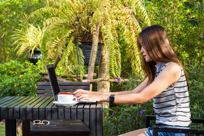 Side view of woman using mobile phone in park