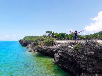 Man standing on rock formation against sky