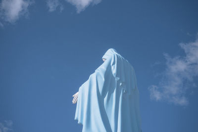 Low angle view of virgin mary statue against blue sky