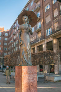 Statue by street against buildings in city