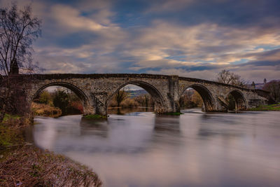 Arch bridge over river against sky