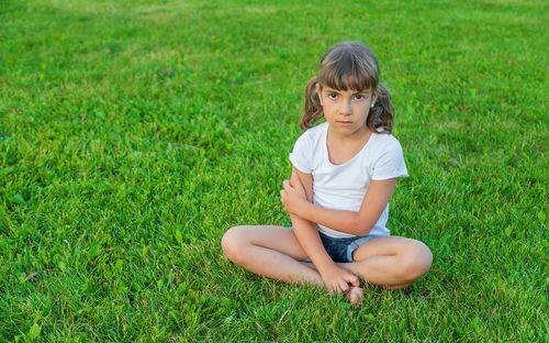 Full length of young woman sitting on grassy field