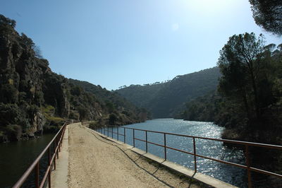 Scenic view of river by mountains against sky