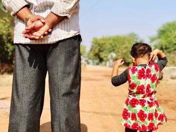 Rear view of father and daughter standing on field