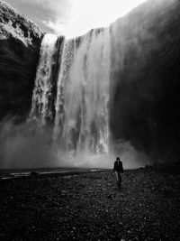 Rear view of man standing against waterfall