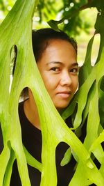 Portrait of smiling woman by green leaves