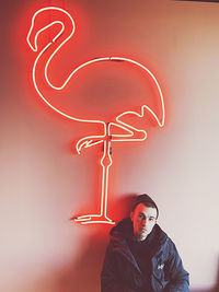 Portrait of young man standing against illuminated wall