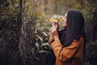 Side view of young woman holding plants