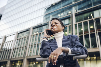 Low angle view of man using mobile phone in city