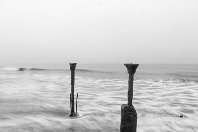 Close-up of wooden post on beach against clear sky