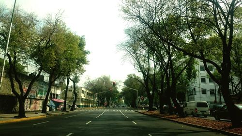 Road amidst trees in city against clear sky