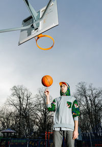 Low angle view of man playing basketball on court against sky