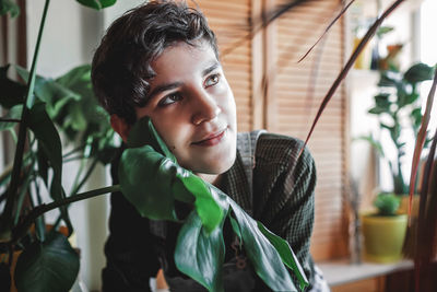 Close-up portrait of young woman holding plant