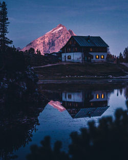 House by lake and mountains against sky