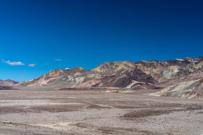 Scenic view of arid landscape against blue sky