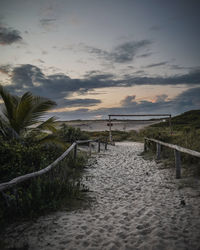 Footpath by sea against sky during sunset