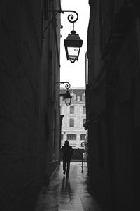 Rear view of woman walking in narrow alley