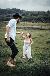 Man holding hands of woman while walking on grassy field