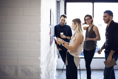 Businesswoman reading paper while colleagues listening to her in creative office