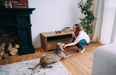 Woman with dog sitting on wooden floor