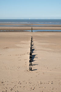 Wooden posts on beach against clear sky