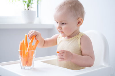 Portrait of cute baby boy eating food at home