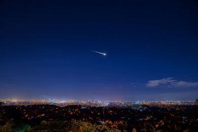 Aerial view of illuminated cityscape against blue sky at night