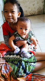 Portrait of cute siblings sitting at home