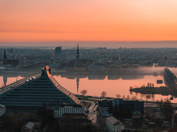 High angle view of townscape by sea against sky during sunset