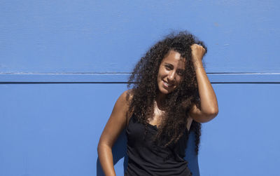 Portrait of a beautiful arabic young woman smiling against blue wall