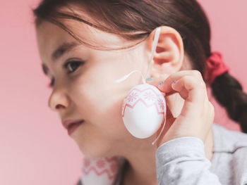 Portrait of a caucasian girl adjusting her hand with an easter egg earring on her ears