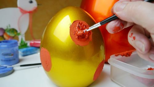 Cropped image of woman painting easter egg at table